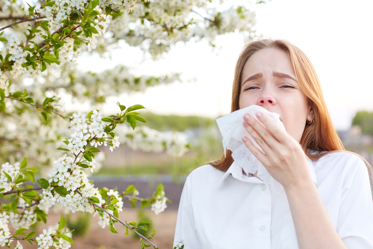 Woman sneezing into a tissue