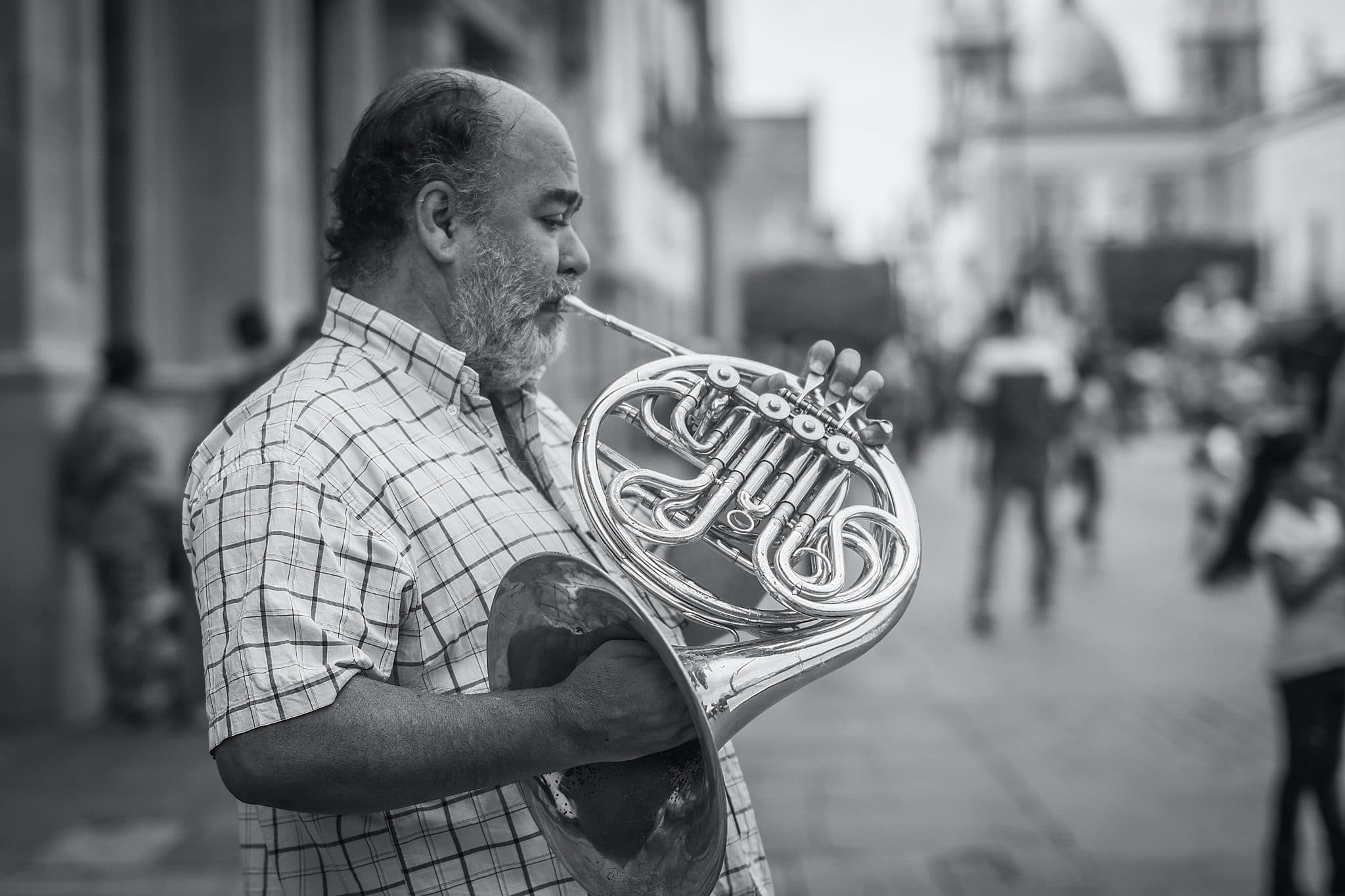 Black and white photo of man playing a French horn