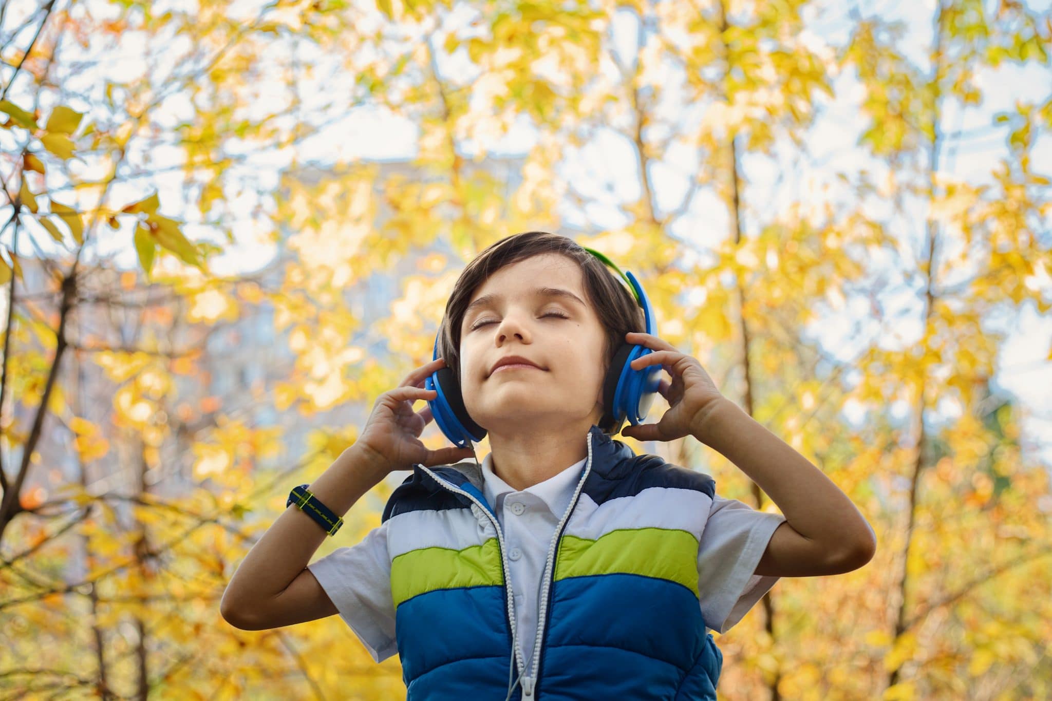 Boy with headphones on with trees in the background