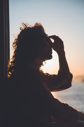 A backlit person pinching the bridge of their nose