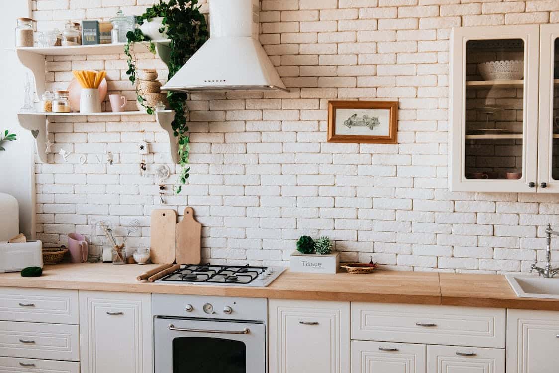 A lovely ranch-style kitchen with a white brick wall and brick cabinets.