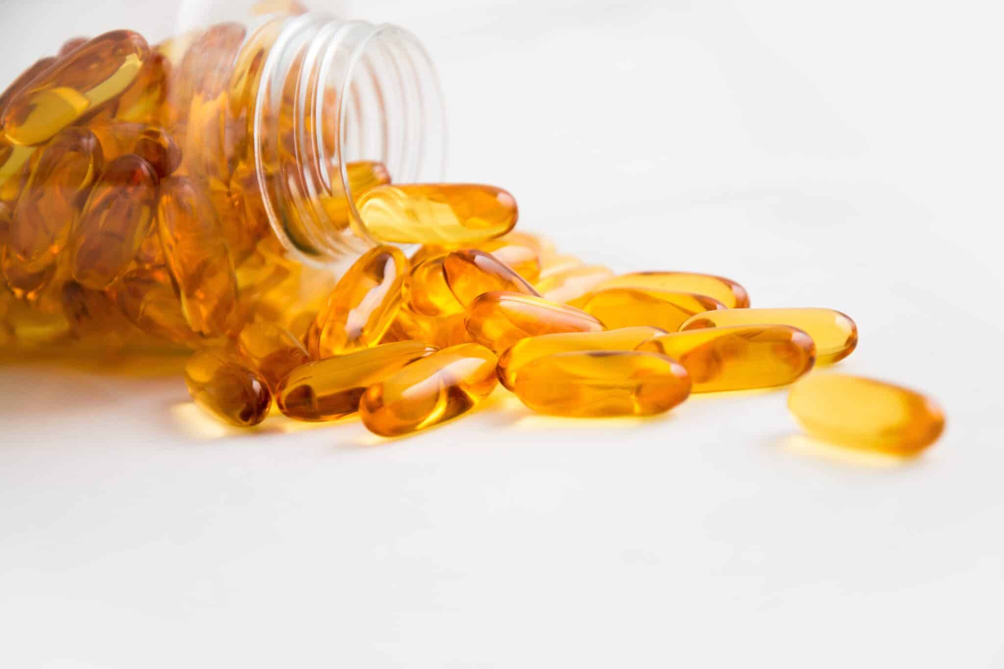 Spilled bottle of yellow capsules against a white background.