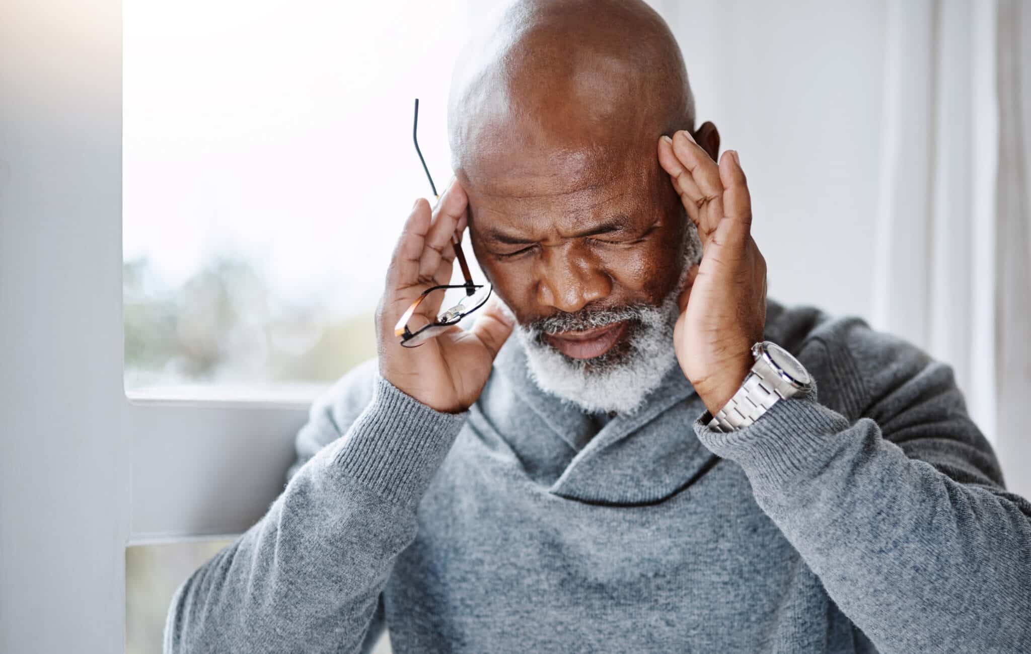 Older man having a headache at home.