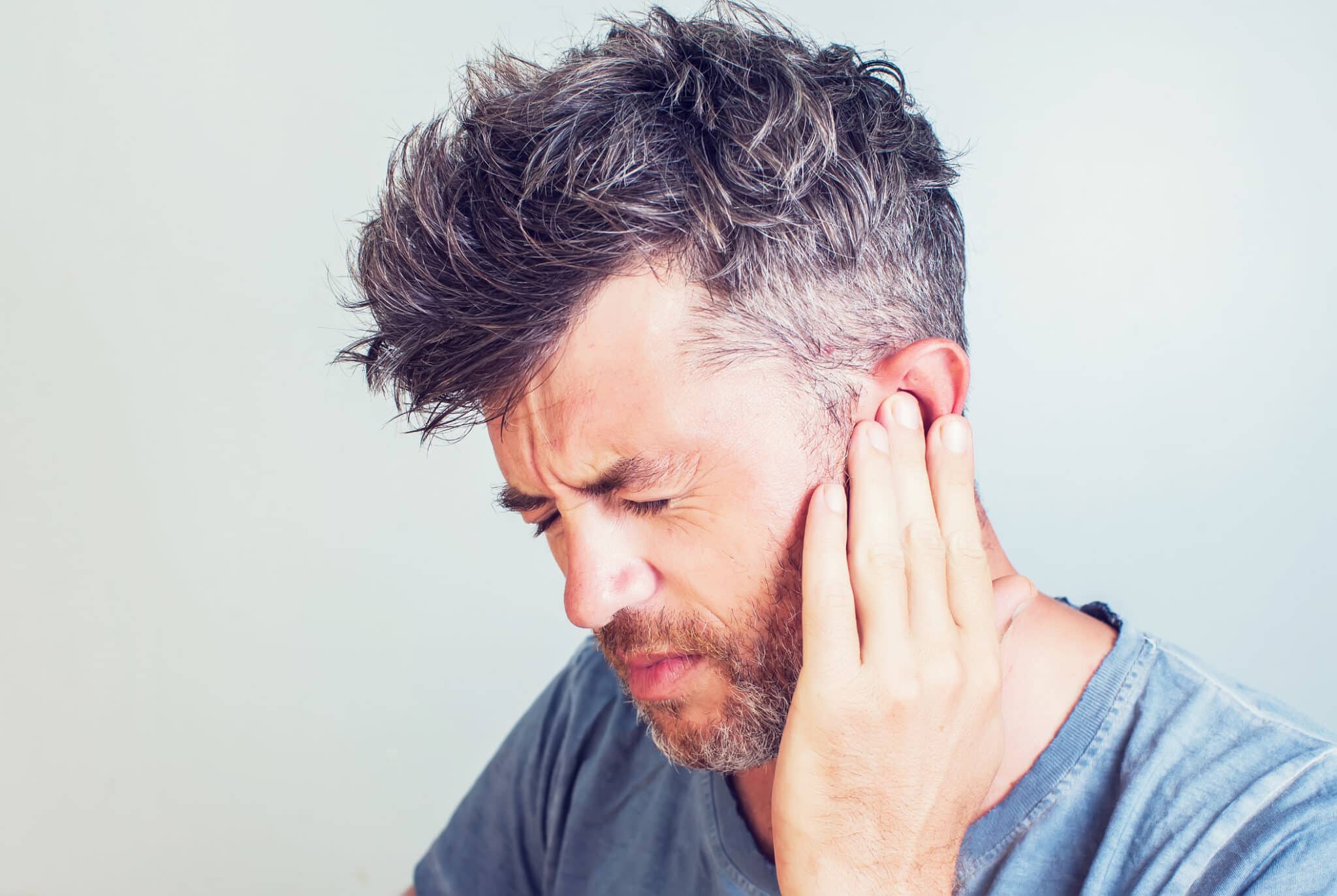 Man with tinnitus putting his hand to his ear.