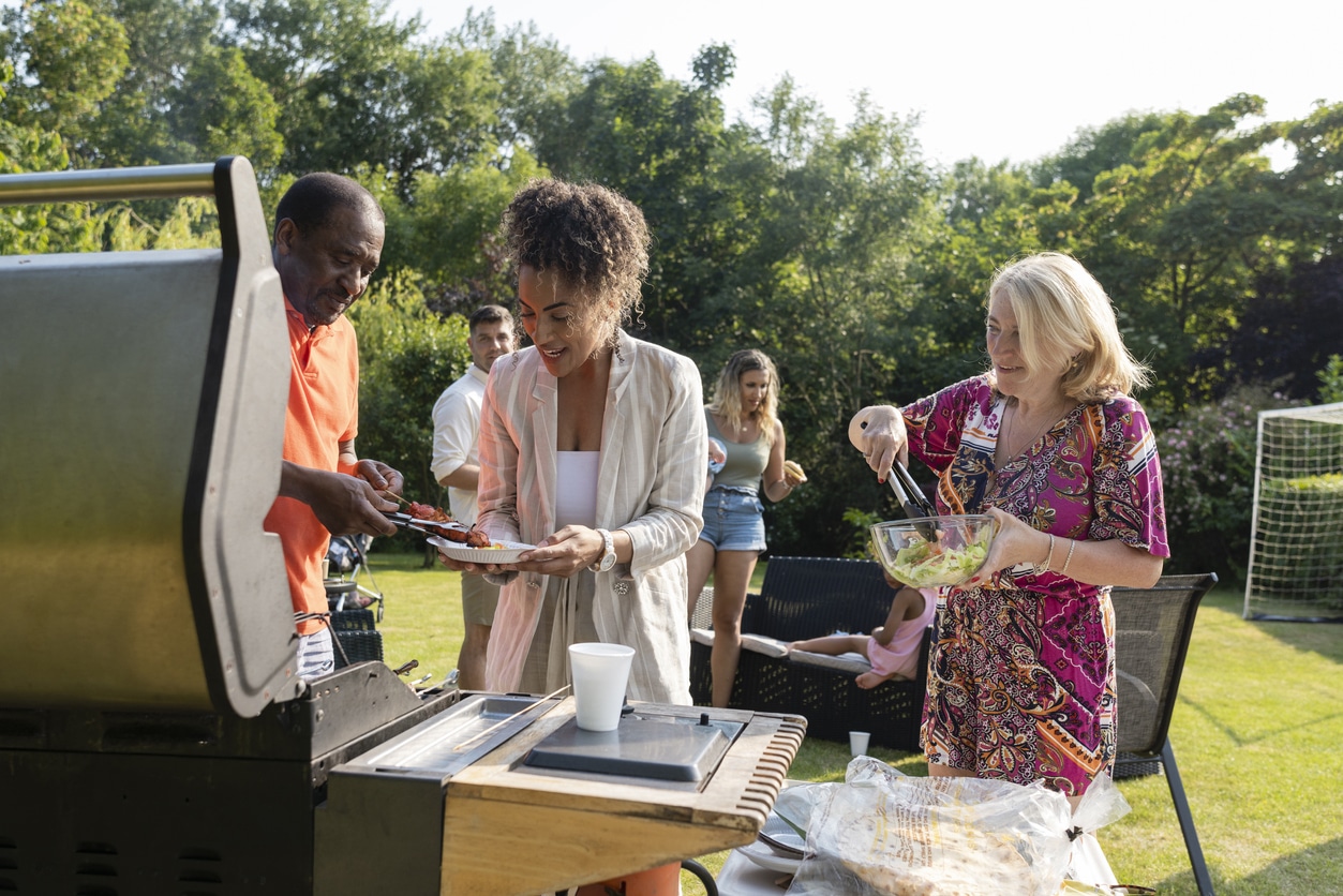 People are serving themselves freshly cooked barbeque in a park setting