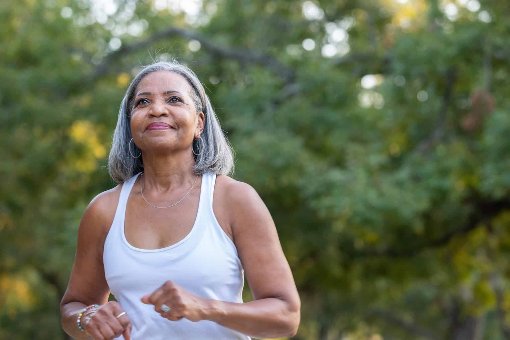 Senior woman jogging in public park.