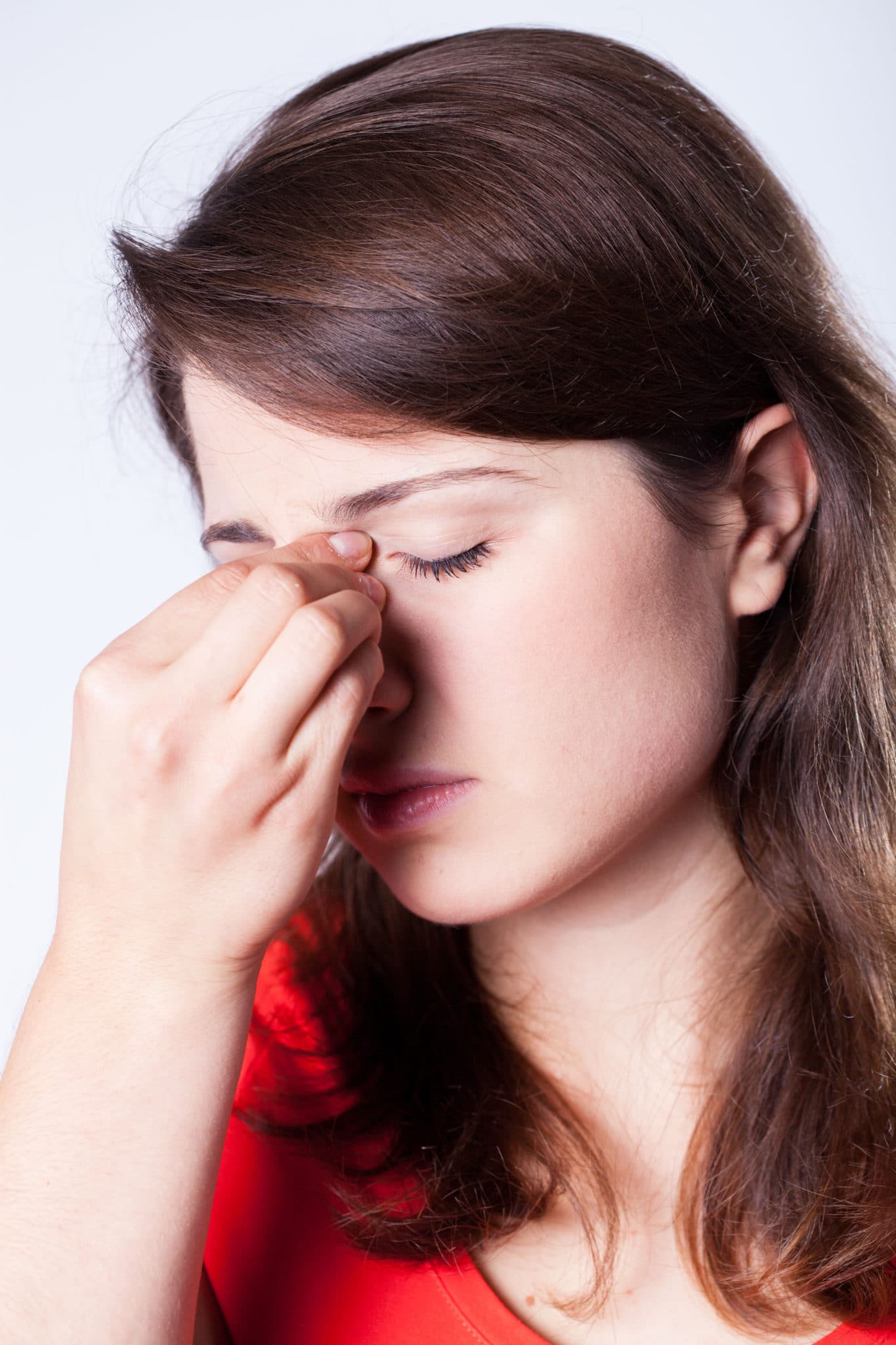 Woman pinching the bridge of her nose and looking distressed