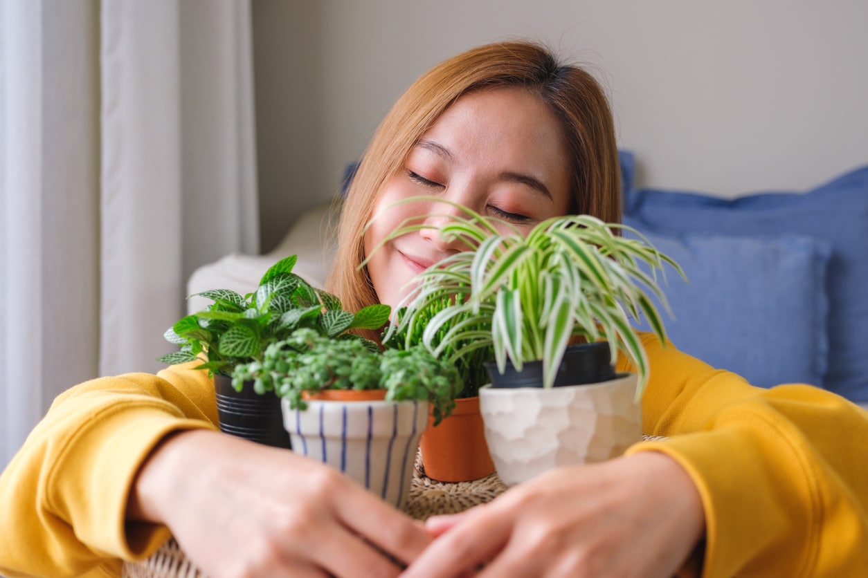 Happy woman holding onto a couple of small house plants