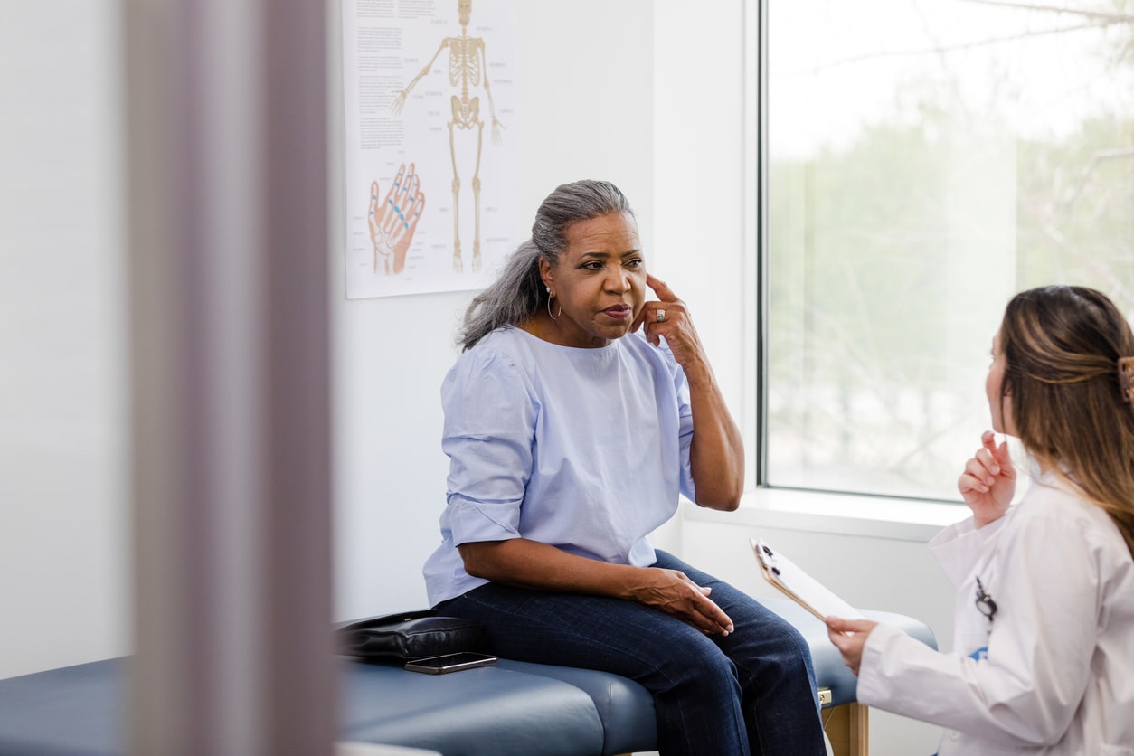 Woman pointing to her ear, talking to audiologist