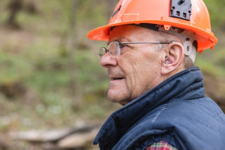 Senior man wearing a hearing aid and hard hat