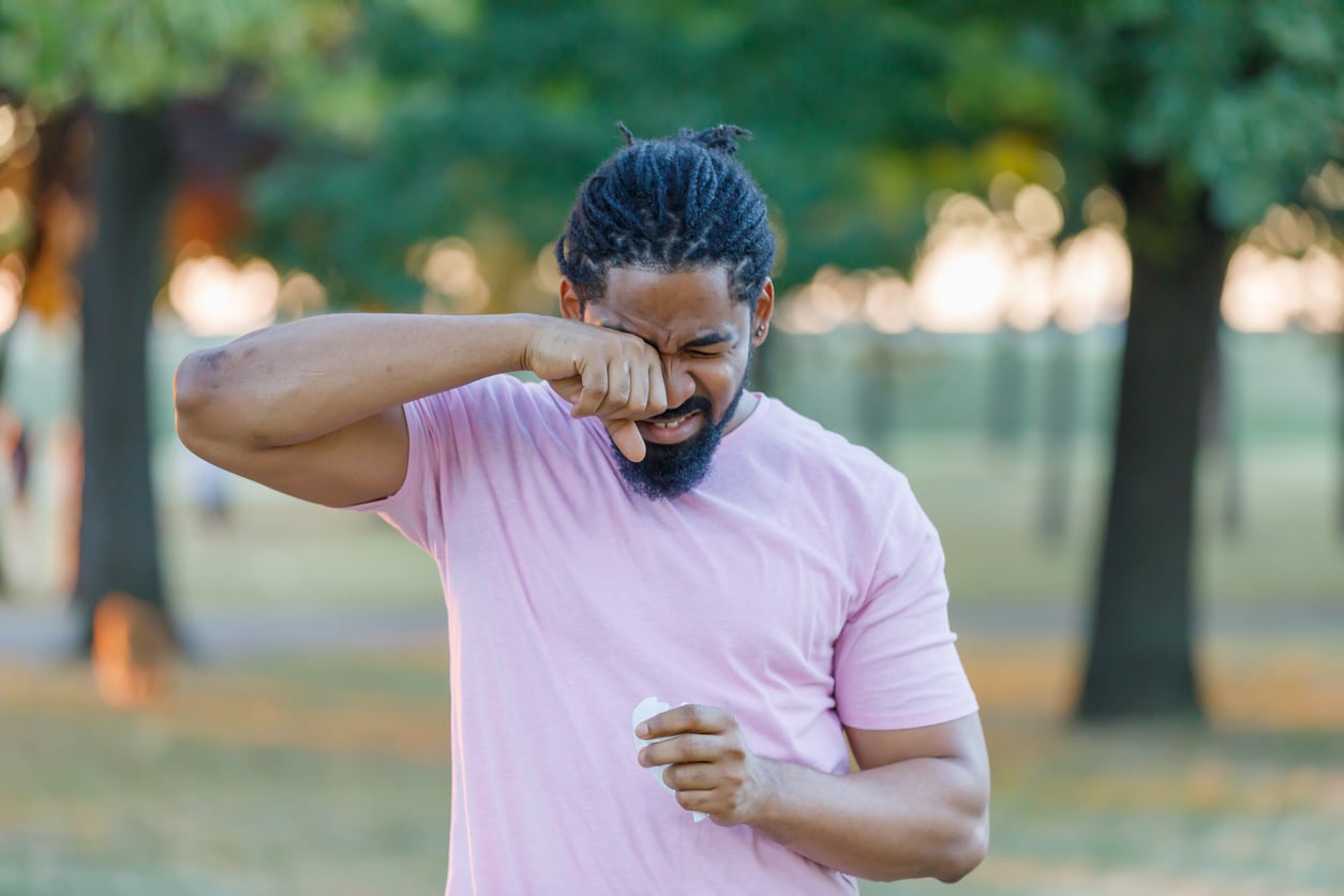 Man scratches eyes in park