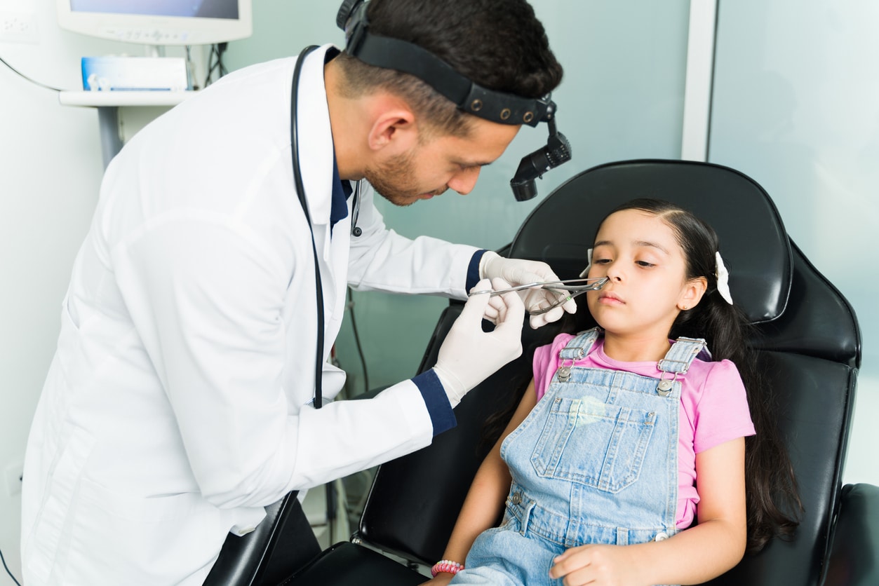 ENT doctor removing an object from a young girl's nose