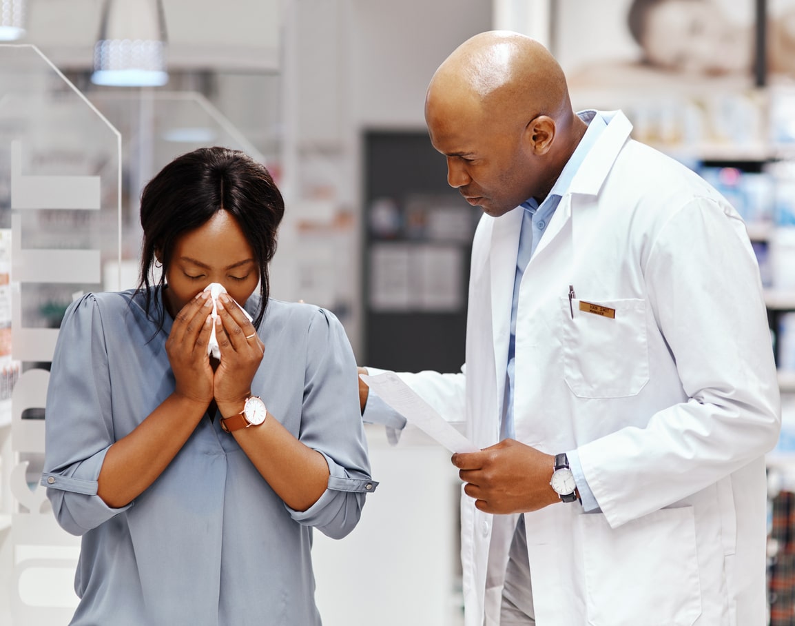 Allergy specialist talking to a patient who's blowing her nose.