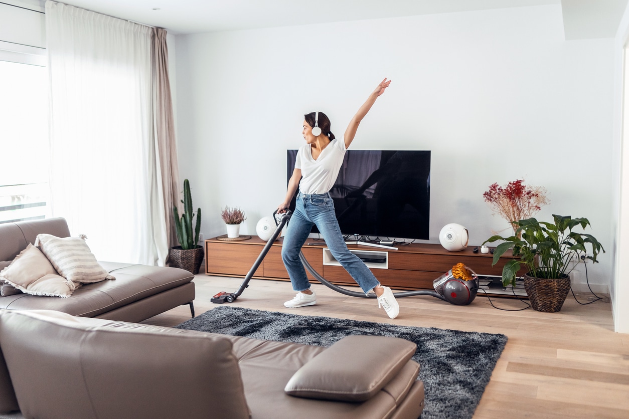 Happy woman vacuuming her home.