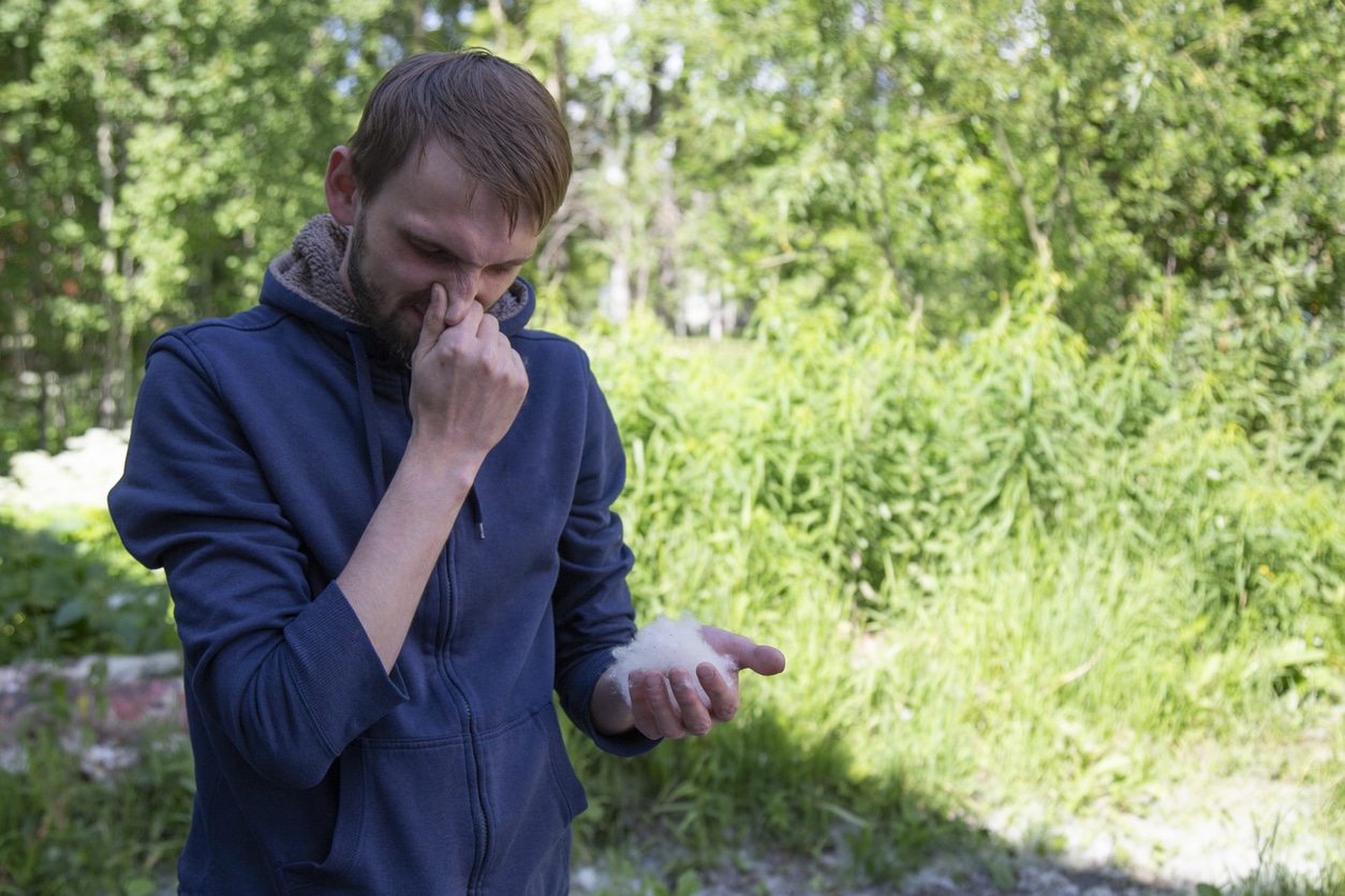 Man sneezing because of pollen in the park.