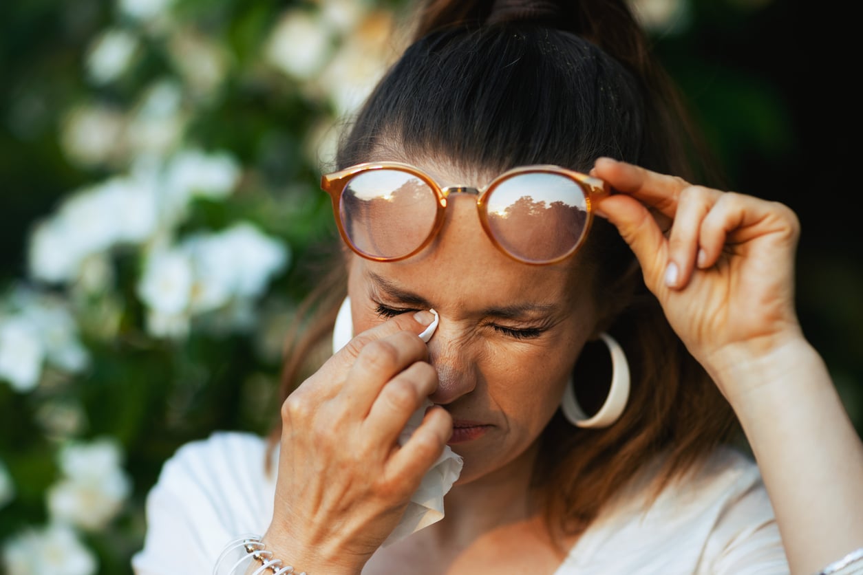 Woman with allergies dabbing her eyes.